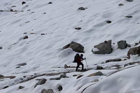 Snow-covered trail leading to Renjo La Pass with a solitary trekker in the distance
