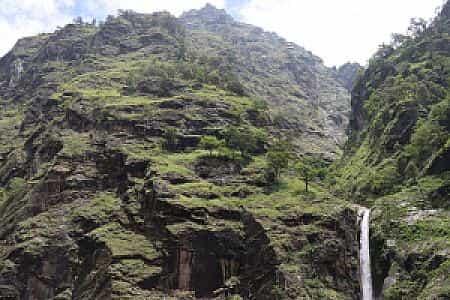 Chyamche Waterfall cascading through lush cliffs along the Annapurna Circuit trail near Jagat, Nepal
