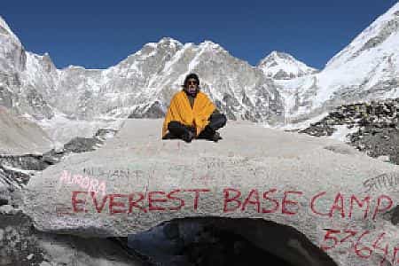 Elderly trekker smiling at Everest Base Camp, dream fulfilled